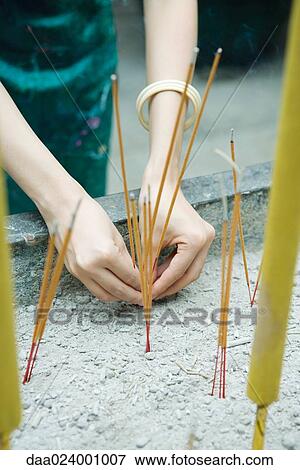 Stock Photo - Woman placing incense in temple censer, cropped view. Fotosearch
