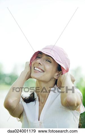 Woman pulling down hat, smiling at camera, portrait View Large Photo Image Stock Photo - Woman pulling down hat, smiling at camera, portrait. Fotosearch