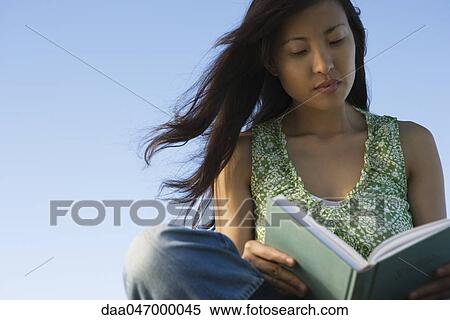 Woman reading book outdoors, hair blowing in breeze View Large Photo Image Stock Photography - Woman reading book outdoors, hair blowing in breeze. Fotosearch