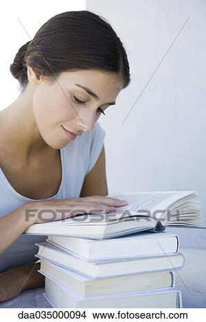 Picture - Woman reading stack of books. Fotosearch