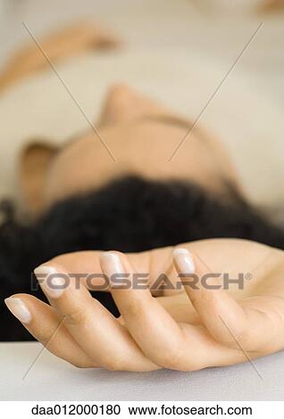 Stock Image - Woman reclining, focus on hand in foreground. Fotosearch