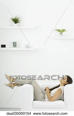 Picture - Woman reclining in armchair, side view. Fotosearch
