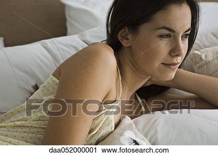 Woman reclining in bed contemplatively looking away View Large Photo Image Stock Image - Woman reclining in bed contemplatively looking away. Fotosearch