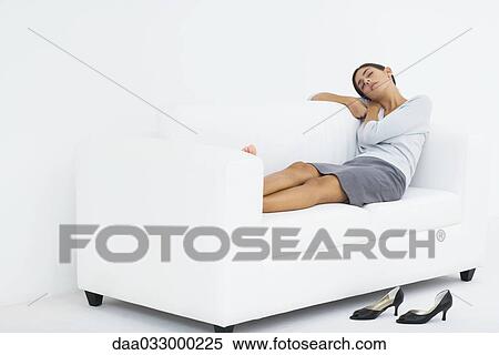 Woman reclining on couch, resting head on her arms, eyes closed View Large Photo Image Stock Photography - Woman reclining on couch, resting head on her arms, eyes closed. Fotosearch