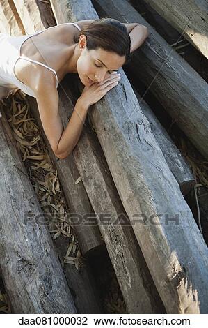Woman reclining on pile of logs View Large Photo Image Stock Image - Woman reclining on pile of logs. Fotosearch