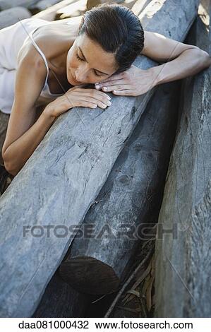 Woman reclining on pile of logs View Large Photo Image Stock Image - Woman reclining on pile of logs. Fotosearch
