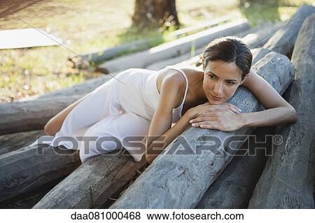 Woman reclining on pile of logs View Large Photo Image Stock Photo - Woman reclining on pile of logs. Fotosearch