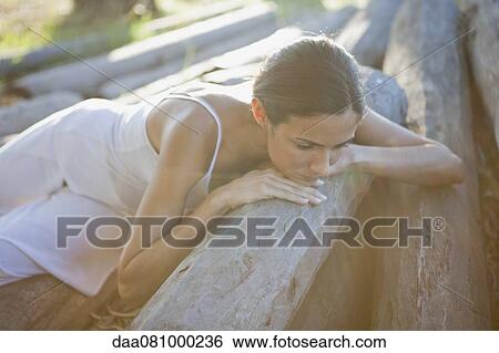 Woman reclining on pile of logs View Large Photo Image Stock Photograph - Woman reclining on pile of logs. Fotosearch