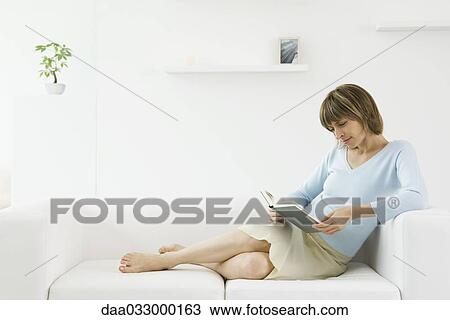 Woman reclining on sofa, reading a book View Large Photo Image Stock Image - Woman reclining on sofa, reading a book. Fotosearch