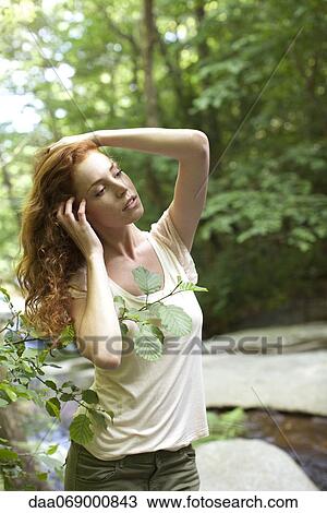 Woman relaxing beside stream with hands in hair View Large Photo Image Stock Image - Woman relaxing beside stream with hands in hair. Fotosearch