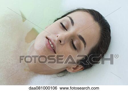 Stock Photograph - Woman relaxing in bath with eyes closed. Fotosearch