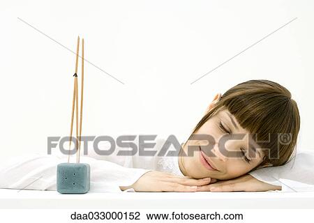 Woman resting head on arm beside incense, smiling with eyes closed View Large Photo Image Stock Image - Woman resting head on arm beside incense, smiling with eyes closed. Fotosearch