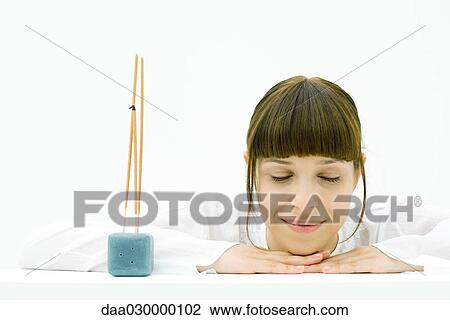 Woman resting head on arms beside incense, eyes closed, smiling View Large Photo Image Stock Image - Woman resting head on arms beside incense, eyes closed, smiling. Fotosearch