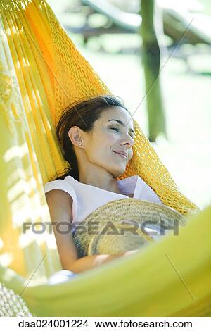 Woman resting in hammock, holding straw hat View Large Photo Image Picture - Woman resting in hammock, holding straw hat. Fotosearch