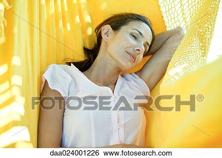 Stock Photograph - Woman resting in hammock, waist up. Fotosearch