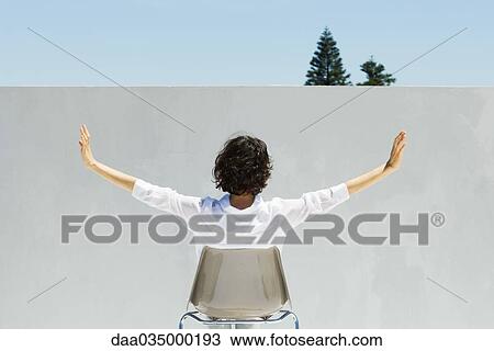 Woman seated facing wall, arms outstretched, rear view View Large Photo Image Stock Image - Woman seated facing wall, arms outstretched, rear view. Fotosearch