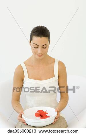 Woman seated holing basin of water with hibiscus flower floating within on her lap View Large Photo Image Stock Image - Woman seated holing basin of water with hibiscus flower floating within on her lap. Fotosearch