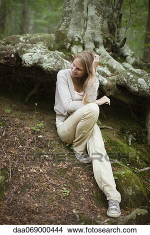 Woman sitting at base of tree in woods View Large Photo Image Picture - Woman sitting at base of tree in woods. Fotosearch