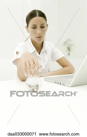 Woman sitting at desk, reaching for glass sphere with her reflection in it View Large Photo Image Stock Image - Woman sitting at desk, reaching for glass sphere with her reflection in it. Fotosearch