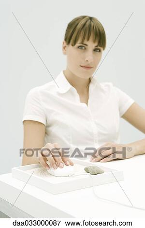 Woman sitting at desk, using computer mouse in small rock garden, smiling at camera View Large Photo Image Stock Photo - Woman sitting at desk, using computer mouse in small rock garden, smiling at camera. Fotosearch