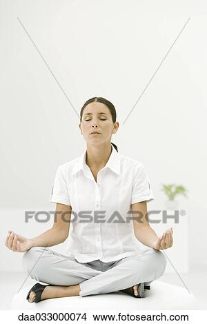 Woman sitting cross-legged, meditating with eyes closed View Large Photo Image Picture - Woman sitting cross-legged, meditating with eyes closed. Fotosearch