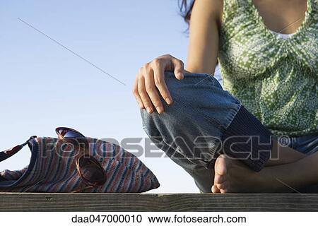 Woman sitting cross-legged on deck, purse and sunglasses beside her, cropped View Large Photo Image Stock Image - Woman sitting cross-legged on deck, purse and sunglasses beside her, cropped. Fotosearch