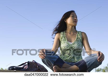 Woman sitting cross-legged outdoors on breezy day, eyes closed View Large Photo Image Stock Image - Woman sitting cross-legged outdoors on breezy day, eyes closed. Fotosearch