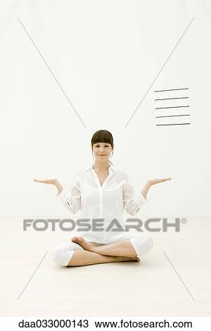 Stock Image - Woman sitting cross-legged with arms out, smiling at camera. Fotosearch