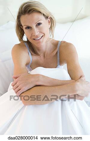 Picture - Woman sitting in bed, looking at camera, smiling. Fotosearch