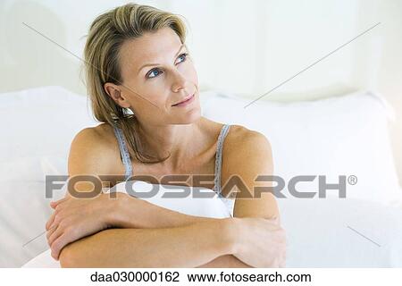 Woman sitting in bed, looking away, smiling View Large Photo Image Stock Image - Woman sitting in bed, looking away, smiling. Fotosearch