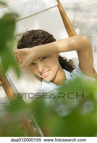 Woman sitting in deck chair, shading eyes, high angle view View Large Photo Image Stock Photography - Woman sitting in deck chair, shading eyes, high angle view. Fotosearch