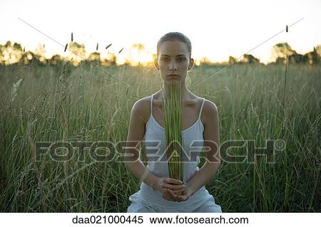 Woman sitting in field, holding rushes in hands View Large Photo Image Stock Photography - Woman sitting in field, holding rushes in hands. Fotosearch