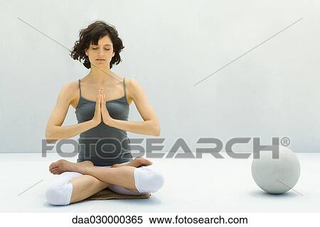 Woman sitting in lotus position beside ball, eyes closed View Large Photo Image Stock Photography - Woman sitting in lotus position beside ball, eyes closed. Fotosearch