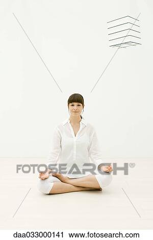 Stock Image - Woman sitting in lotus position, smiling at camera. Fotosearch