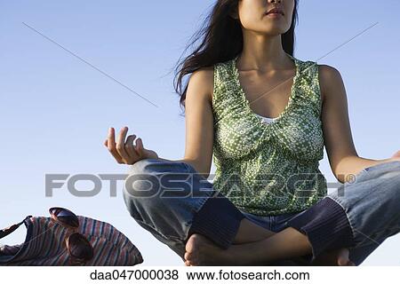 Stock Photo - Woman sitting in lotus position outdoors, cropped. Fotosearch