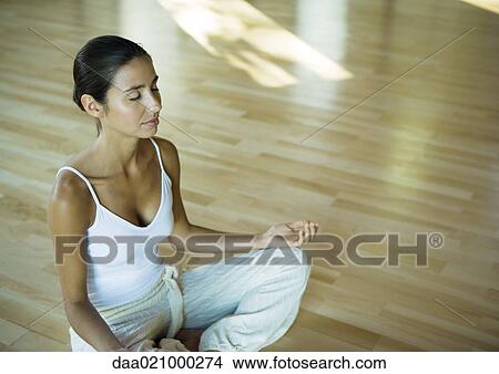 Picture - Woman sitting in lotus position with eyes closed. Fotosearch