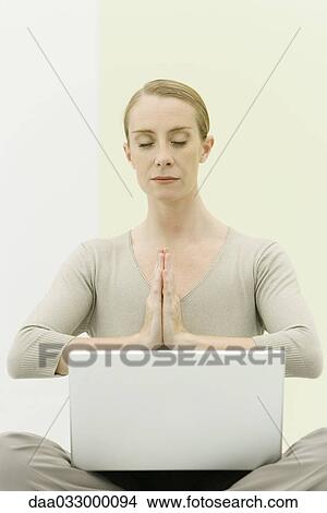 Woman sitting in prayer position, eyes closed, holding laptop computer on her lap View Large Photo Image Picture - Woman sitting in prayer position, eyes closed, holding laptop computer on her lap. Fotosearch