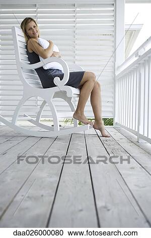 Woman sitting in rocking chair on porch, hugging pillow, smiling at camera View Large Photo Image Stock Image - Woman sitting in rocking chair on porch, hugging pillow, smiling at camera. Fotosearch