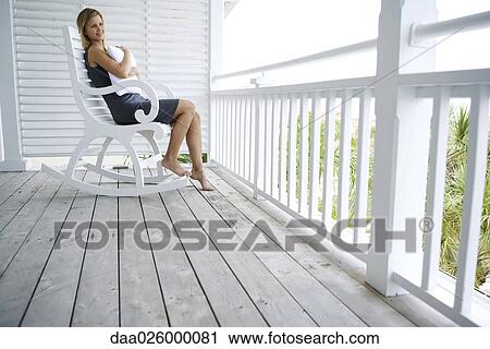 Woman sitting in rocking chair on porch, hugging pillow, looking away View Large Photo Image Stock Image - Woman sitting in rocking chair on porch, hugging pillow, looking away. Fotosearch