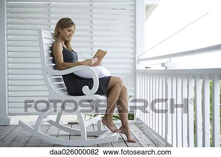 Woman sitting in rocking chair on porch, reading book View Large Photo Image Stock Image - Woman sitting in rocking chair on porch, reading book. Fotosearch