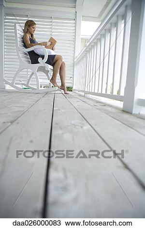 Woman sitting in rocking chair on porch, reading book, low angle view View Large Photo Image Stock Image - Woman sitting in rocking chair on porch, reading book, low angle view. Fotosearch