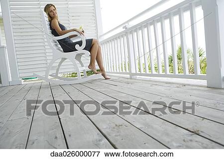 Woman sitting in rocking chair on porch, holding flower, smiling at camera View Large Photo Image Stock Photo - Woman sitting in rocking chair on porch, holding flower, smiling at camera. Fotosearch