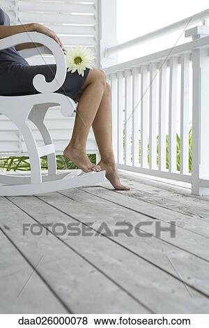 Woman sitting in rocking chair on porch, holding flower on lap, cropped view View Large Photo Image Stock Photo - Woman sitting in rocking chair on porch, holding flower on lap, cropped view. Fotosearch
