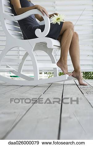 Woman sitting in rocking chair on porch, holding flower on lap, cropped view View Large Photo Image Stock Photo - Woman sitting in rocking chair on porch, holding flower on lap, cropped view. Fotosearch