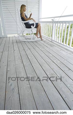 Woman sitting in rocking chair on porch, holding flower, side view View Large Photo Image Stock Photography - Woman sitting in rocking chair on porch, holding flower, side view. Fotosearch