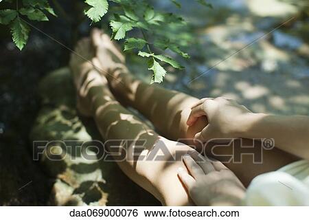 Stock Photograph - Woman sitting in shadow of tree branches, cropped. Fotosearch