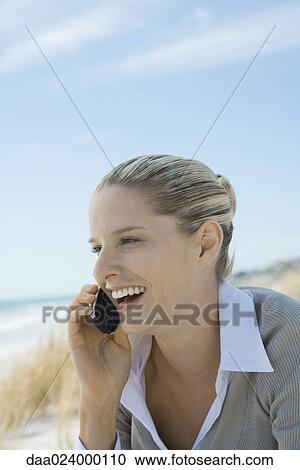 Woman sitting on dunes at beach, using cell phone, close-up View Large Photo Image Stock Image - Woman sitting on dunes at beach, using cell phone, close-up. Fotosearch