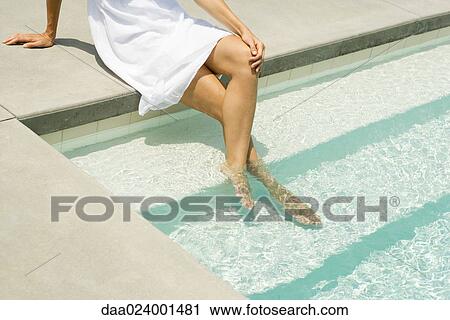 Woman sitting on edge of pool, feet in water, high angle view, cropped View Large Photo Image Stock Image - Woman sitting on edge of pool, feet in water, high angle view, cropped. Fotosearch
