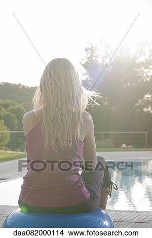 Woman sitting on fitness ball at poolside, rear view View Large Photo Image Picture - Woman sitting on fitness ball at poolside, rear view. Fotosearch