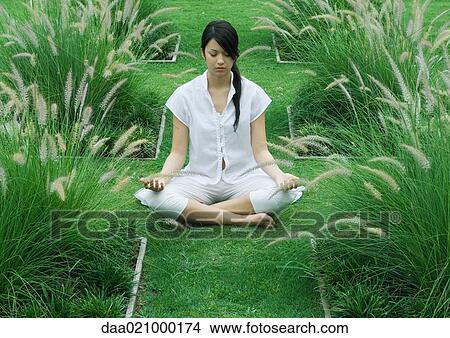 Picture - Woman sitting on grass in lotus position. Fotosearch